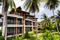 a building with palm trees in front of it at Maehaad Bay Resort - SHA Plus in Mae Haad