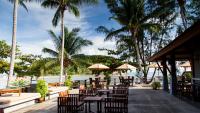 a restaurant with tables and chairs and palm trees at Maehaad Bay Resort - SHA Plus in Mae Haad