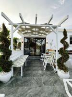 a patio with white benches and a pergola at Skiathos Holiday Resort in Skiathos