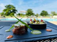ein Teller mit Essen auf einem Tisch neben einem Pool in der Unterkunft Le Noirlac in Saint-Amand-Montrond