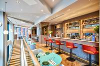a restaurant with red chairs and a bar at Maldron Hotel Manchester Cathedral Quarter in Manchester