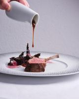 a person pouring sauce on a piece of food on a plate at La Villa Mauresque in Saint-Raphaël