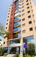 a tall building with a purple sign in front of it at Guará Inn Flat Service in Guaratinguetá