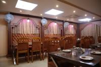 Un comedor con mesas y sillas y ventanas. en Hotel Sai International, en Paralākhemundi