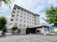 un gran edificio blanco con aparcamiento en Hotel Route-Inn Iida, en Iida