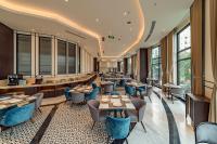 Un restaurante con mesas, sillas y ventanas. en Charmant Suites a Boutique Hotel Can Tho, en Can Tho