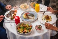 un grupo de personas sentadas en una mesa con platos de comida en DAMAC Maison Aykon City Dubai, en Dubái