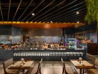 バンコクにあるアマラバンコクホテルのテーブルと椅子とキッチンのあるレストラン