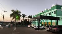 un edificio verde con coches aparcados en un aparcamiento en Papagaio Hotel, en Guaíra