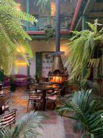 Un restaurante con chimenea, mesas y plantas. en Hotel Posada de San Agustin, en Tunja