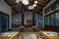 a restaurant with wooden tables and chairs and windows at Mount Emei Heyuan Serene Residence Hot Spring Hotel in Emeishan