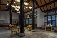 a dining room with tables and chairs and windows at Mount Emei Heyuan Serene Residence Hot Spring Hotel in Emeishan