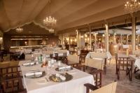 Gmundner Lodge في ويندهوك: مطعم ذو طاولات وكراسي وثريات بيضاء