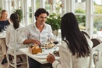Un grupo de personas sentadas alrededor de una mesa comiendo comida en Hotel Rusthållargården, en Arild