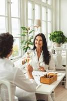Dos mujeres sentadas en una mesa con una copa de vino en Hotel Rusthållargården, en Arild