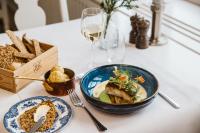 Una mesa con un plato de comida y una copa de vino. en Hotel Rusthållargården, en Arild