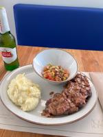 Un plato con carne y puré de papas y un tazón de comida en Hotel Aqua House, en Tubará