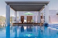 Una piscina con una sombrilla al lado de una casa. en Comfort Inn &amp; Suites Los Cabos, en Cabo San Lucas