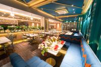 Un restaurante con sofás y mesas azules y flores. en The All - Suite Pentacity Hotel Balikpapan, en Balikpapan