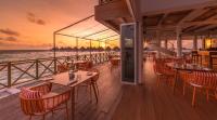 un restaurante en un crucero con mesas y sillas en Mercure Maldives Kooddoo - Adults-Only Escape - 50 percent off Domestic Transfers, en Gaafu Alifu Atoll
