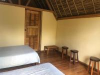 a bedroom with a bed and two stools and a door at Soanala in Moramanga