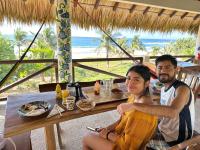 a man and a woman sitting at a table in front of the beach at Beachfront Paradise Boutique Hotel - Alebrijes Jacuzzi Villa in Playa Agua Blanca