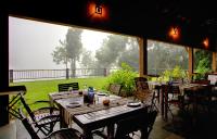 a room with tables and chairs and a large window at Rainforest Resort in Athirappilly