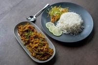 Dos platos de comida en una mesa con arroz y un plato de comida. en Hotel Nandini, en Dhaka