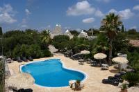 una piscina con sombrillas y sillas y un complejo en Masseria Pentima Vetrana Resort, en Alberobello