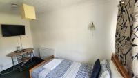 a bedroom with a bed and a table and a television at Gatwick Castle B&B in Horley
