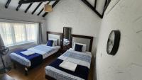 a bedroom with two beds and a clock on the wall at Gatwick Castle B&B in Horley