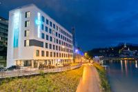 a hotel building next to a river at night at Motel One Salzburg-Mirabell in Salzburg