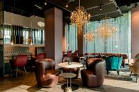 a restaurant with leather chairs and a table and a chandelier at Motel One Salzburg-Mirabell in Salzburg