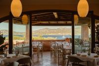 Un restaurante con mesas y sillas y vista al mar. en Aethos Sardinia, en Cannigione