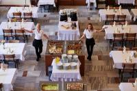 スリアチにあるHotel Palace - KÚPELE SLIAČのテーブルに食べ物を置いてレストランに立っている2人の女性