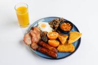 a plate of breakfast food with eggs sausage and beans and a glass of juice at Ramada by Wyndham Belfast in Belfast