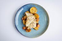 a blue plate with fish and vegetables with a lemon at Ramada by Wyndham Belfast in Belfast