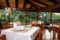 un ristorante con tavoli e sedie bianchi e finestre di La Jacia Hotel & Resort a Baja Sardinia