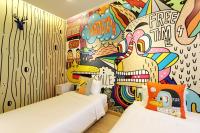 two beds in a room with a wall covered in graffiti at Beat Hotel Bangkok in Bangkok