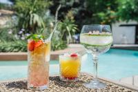 Dos cócteles y una copa de vino en una mesa junto a una piscina. en Setclub Hôtel & Spa Aix-en-Provence, en Aix-en-Provence
