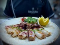 un piatto di cibo con frutti di mare e verdure su un tavolo di Ragusa Villa a Stolac