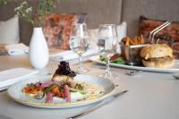 ナントにあるBrit Hotel Nantes La Beaujoire Parc Expoのテーブルの上に置かれたワイングラスの置かれた料理の皿