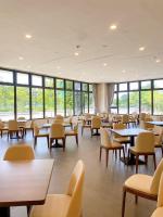 Un comedor con mesas y sillas y ventanas. en Floramos Hotel, en Tianzhong