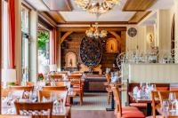 un restaurante con mesas y sillas de madera y una lámpara de araña en Hotel Unter den Linden, en Rüdesheim am Rhein