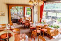 Un restaurante con mesas y sillas y un gran ventanal. en Hotel Unter den Linden, en Rüdesheim am Rhein