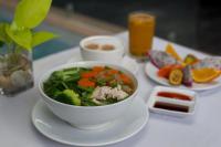 a bowl of vegetables on a white plate on a table at Solitaire Damnak Villa Hotel in Siem Reap
