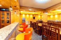 um restaurante com paredes de madeira e um bar com cadeiras laranjas em The Golden Retreat Hotel in Pelling em Pelling