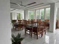 uma sala de jantar com mesa, cadeiras e janelas em The Shalam Resort श्रीकृष्ण शरणं मम em Lansdowne
