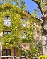 Un edificio cubierto de hiedra con sillas y un árbol. en Logis hotel Noemys Gradignan, en Gradignan