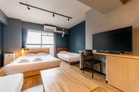a bedroom with two beds and a flat screen tv at e-stay namba in Osaka